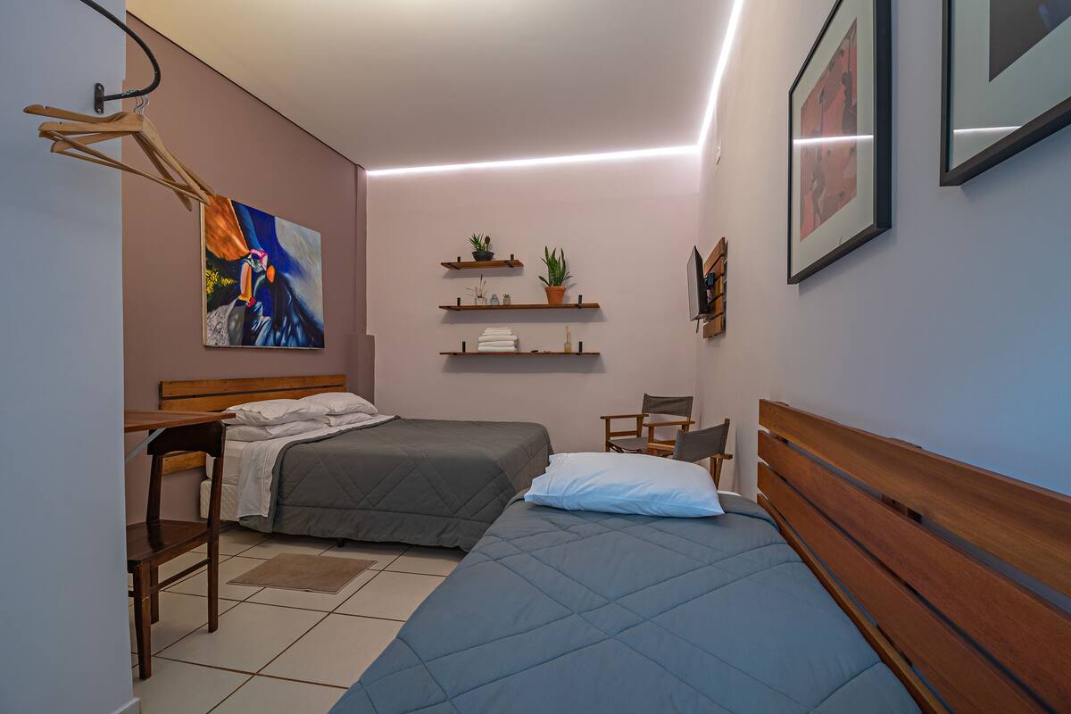 Un dormitorio con dos camas, una silla de madera, un escritorio y estantes con plantas.