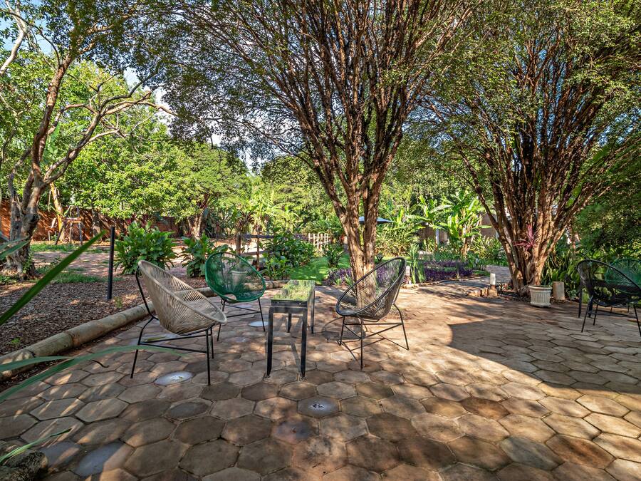 An outdoor patio area with hexagonal stone flooring, surrounded by lush greenery and trees.