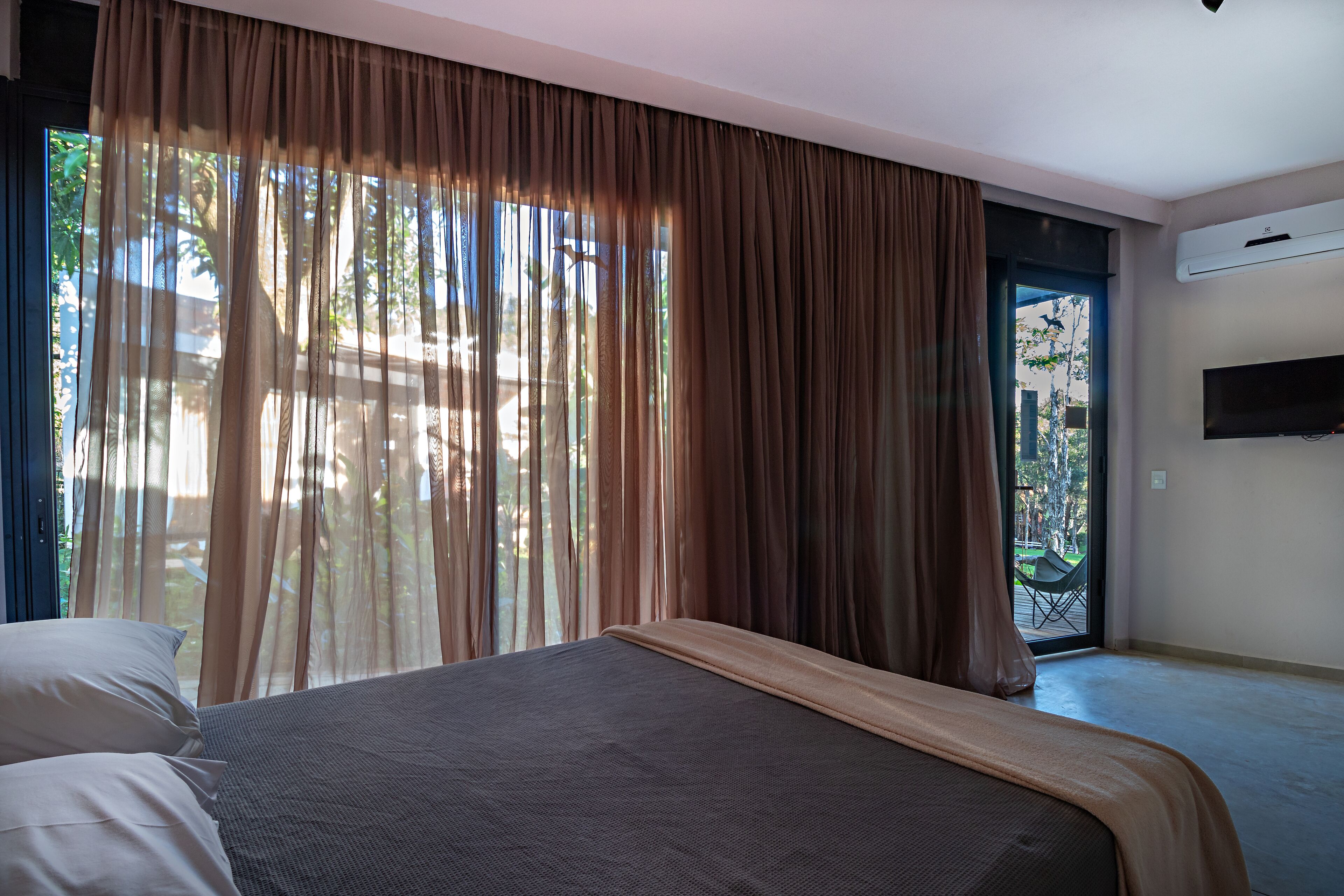 Une chambre d’hôtel avec un lit, des rideaux, une télévision et une vue sur l’extérieur.