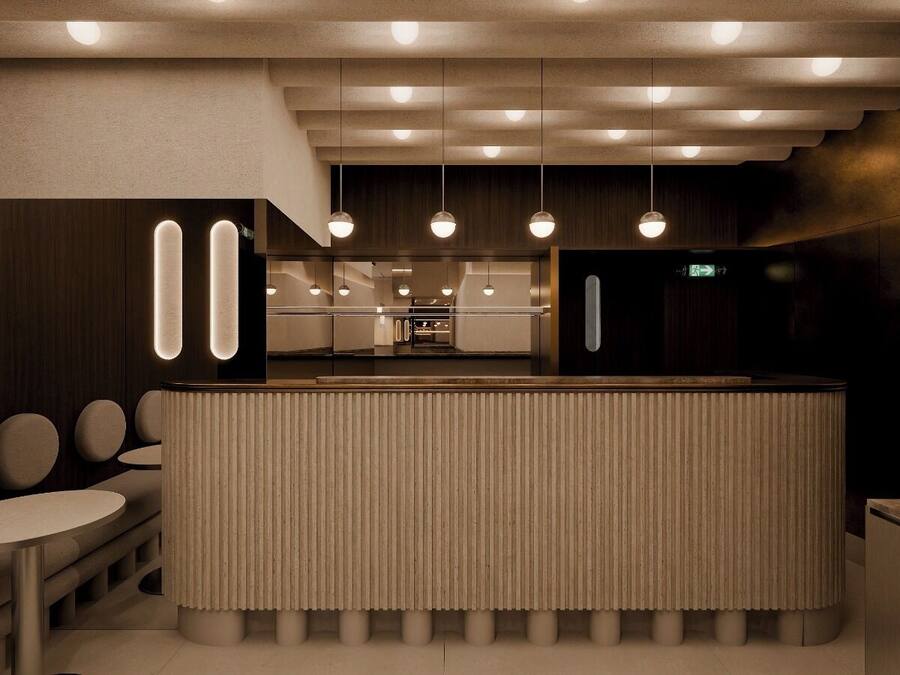 Un interior moderno con una barra central, mesas redondas e iluminación colgante.