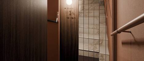 A modern interior with a wooden floor, a marble staircase, and a wall-mounted light fixture.