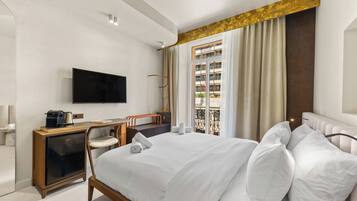 A modern hotel room with a bed, a desk, a television, and a window with curtains.
