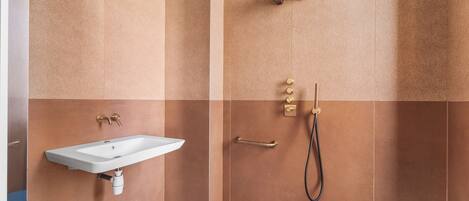 A bathroom with a sink, shower, and towel rack.