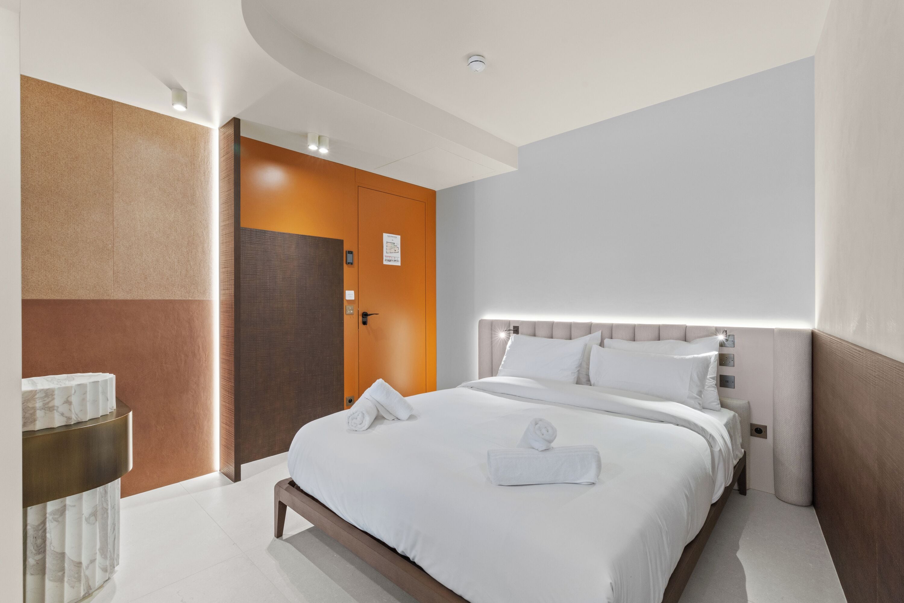 Una habitación de hotel moderna con una cama grande, una mesita de noche y una puerta.