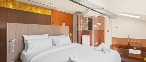 Una habitación de hotel moderna con una cama grande, una bañera integrada y un cabecero de madera.