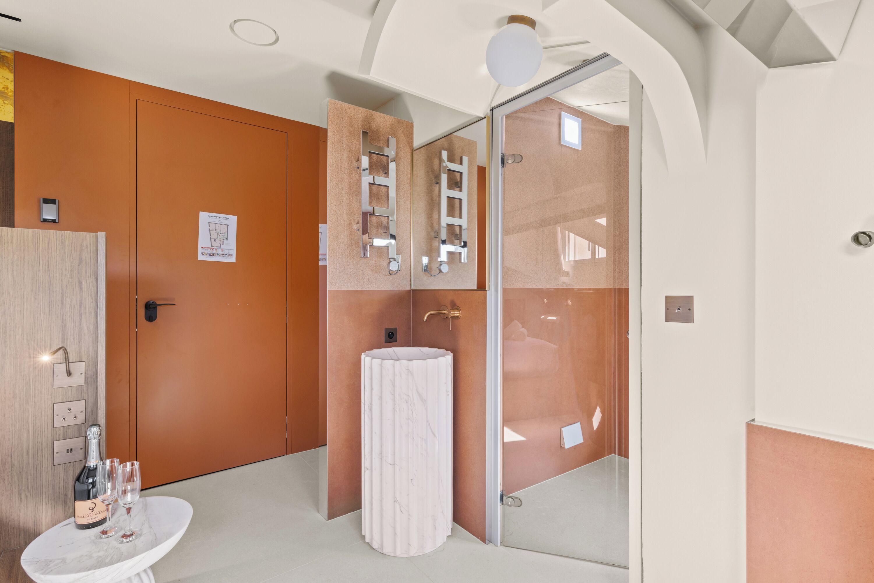 A modern bathroom with a marble sink, a mirror with a ladder design, and a wooden door.