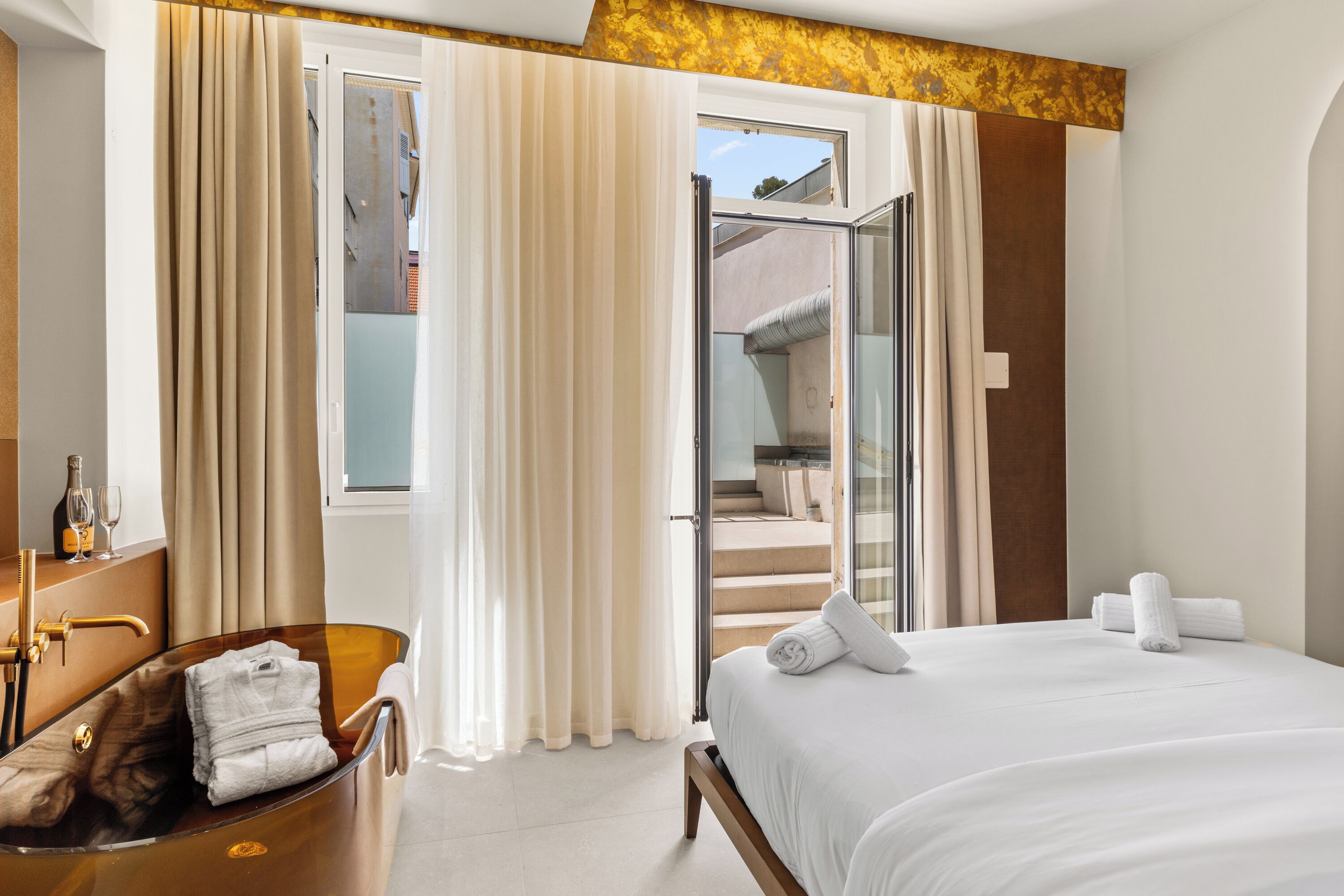 Ein Hotelzimmer mit einer Glaskabinentubus, einem Bett mit weißen Leinen und Blick ins Freie.