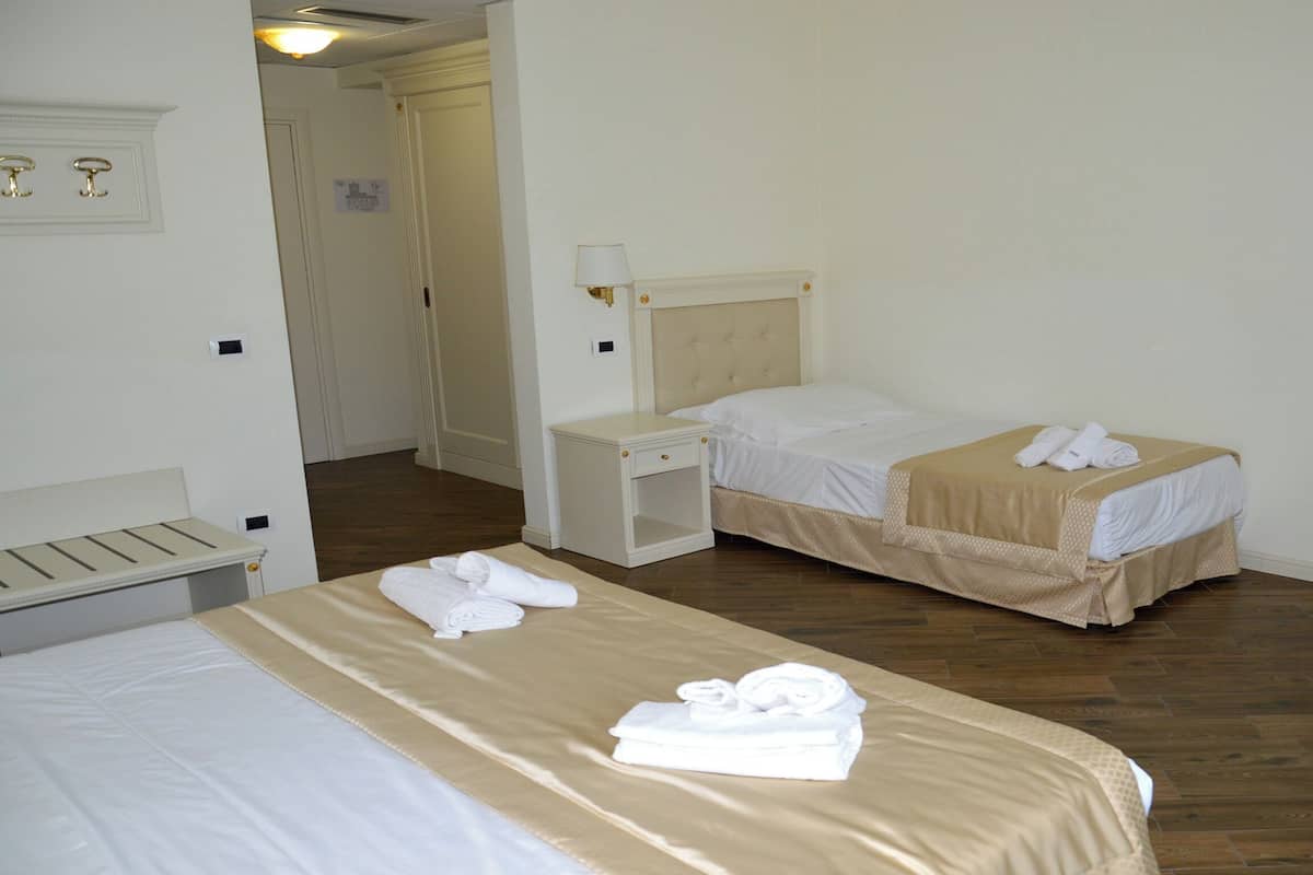 A hotel room with two beds, a desk, and a chair.