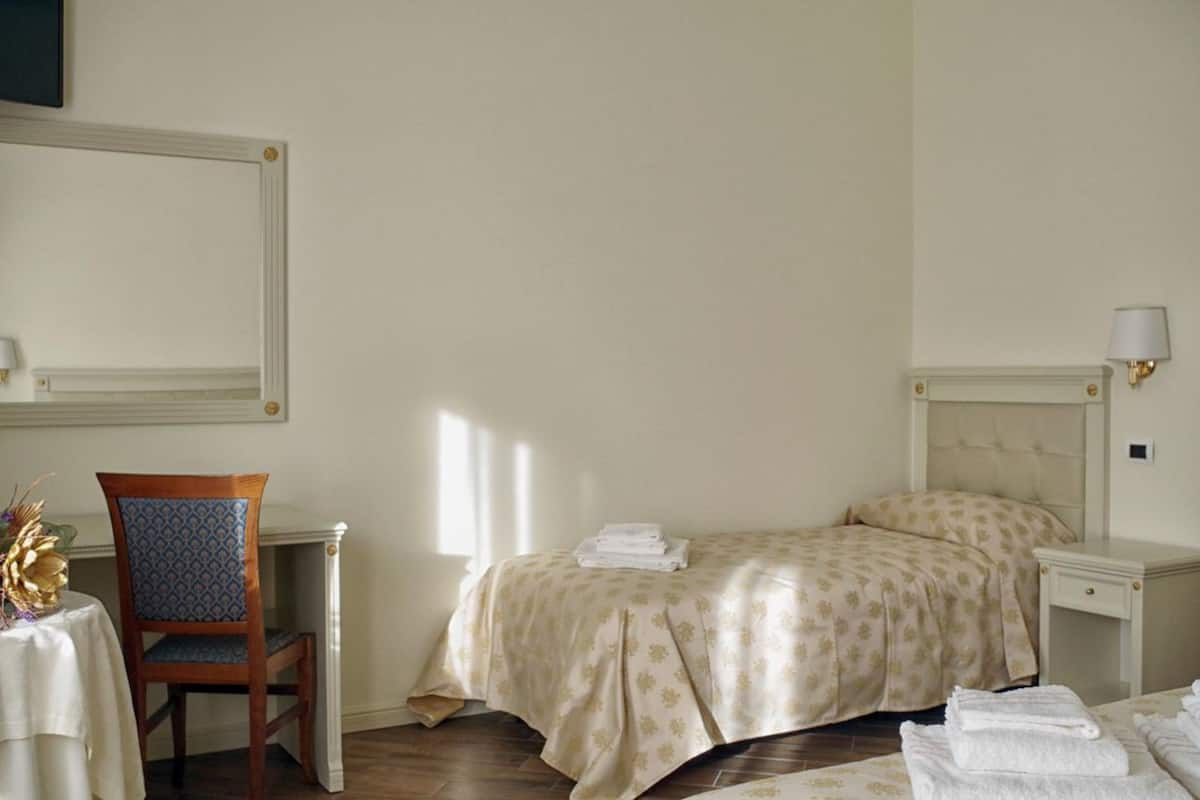 A hotel room with a bed, a chair, a table, and a lamp.