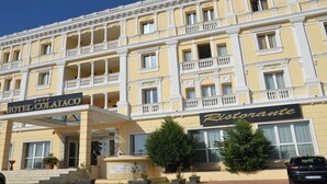 Um hotel de vários andares com fachada amarela, varandas e um letreiro de restaurante.