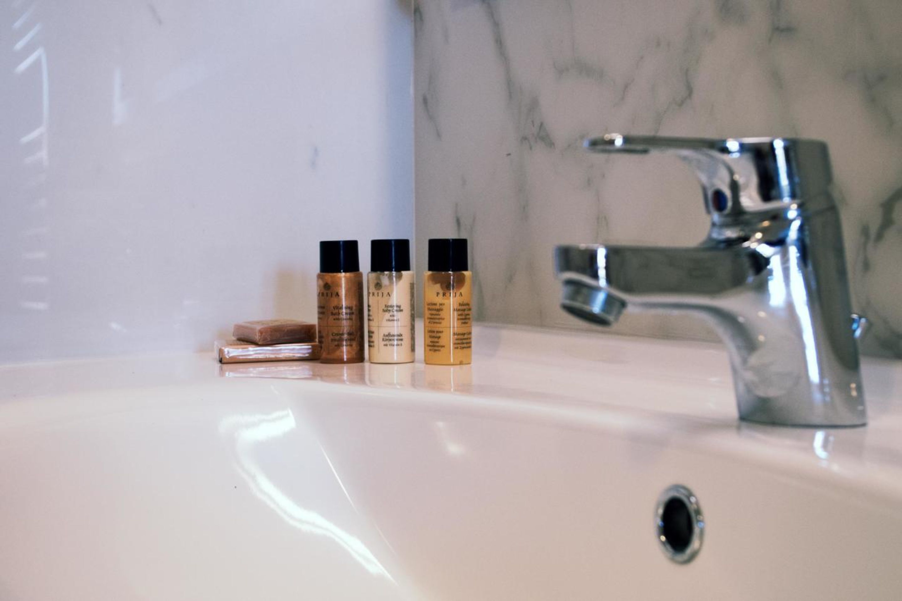 Un lavabo de salle de bain avec trois flacons de savon liquide et un pain de savon.