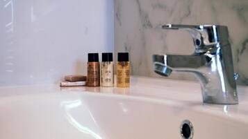 Un lavabo de salle de bain avec trois flacons de savon liquide et un pain de savon.