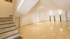 Ett rymligt interiört utrymme med ett polerat klinkergolv, en trappa med ett ledstång och ett inramat konstverk på väggen.