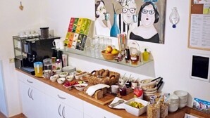 Un bufé de desayuno con diversas opciones de comida, una máquina de café y un cuadro en la pared.
