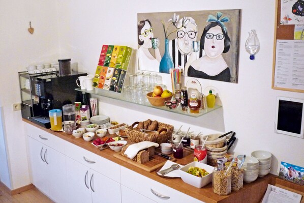 Un bufé de desayuno con diversas opciones de comida, una máquina de café y un cuadro en la pared.