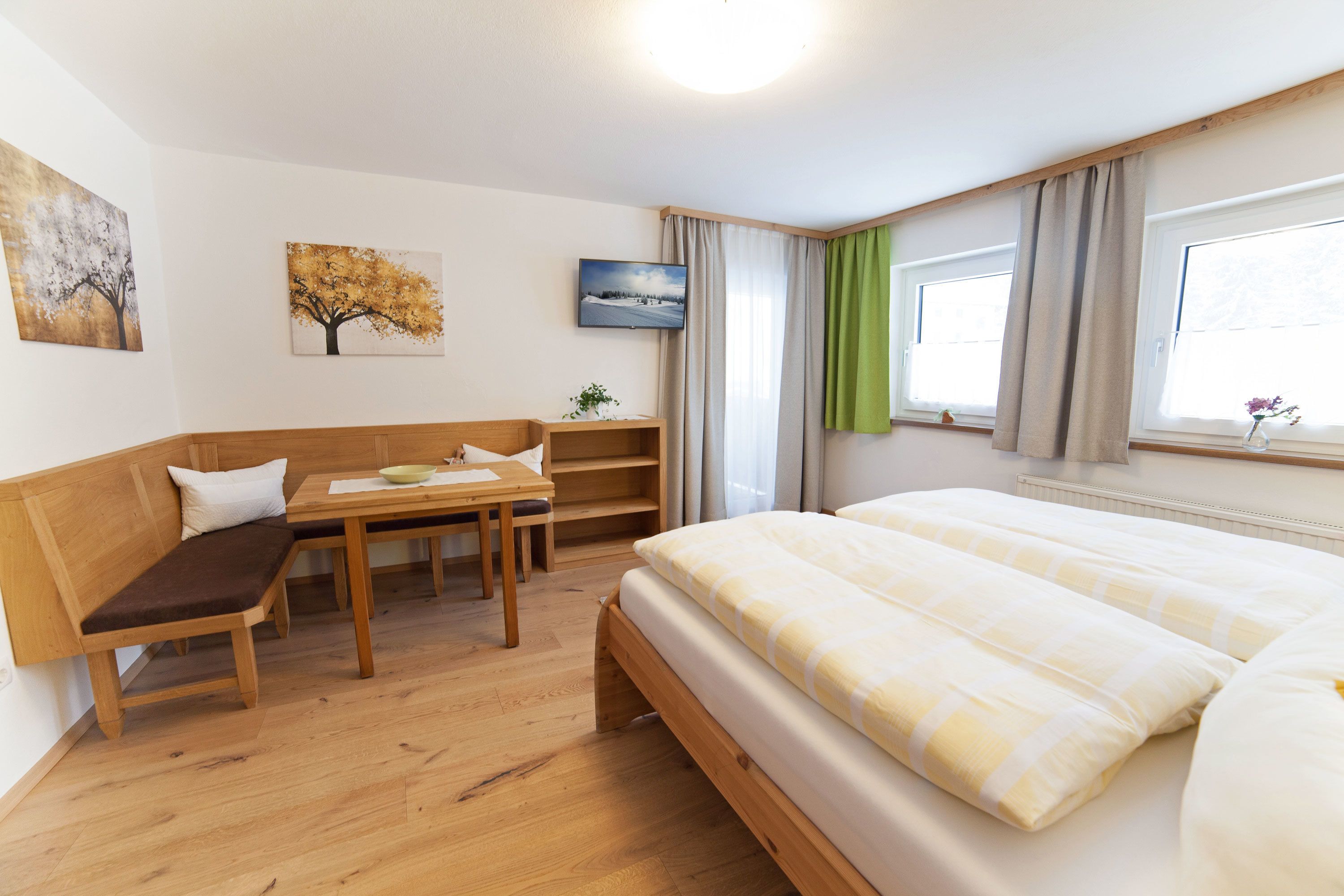 Een hotelkamer met een bed, een houten bankje, een tafel met een kom en een kleine plant.