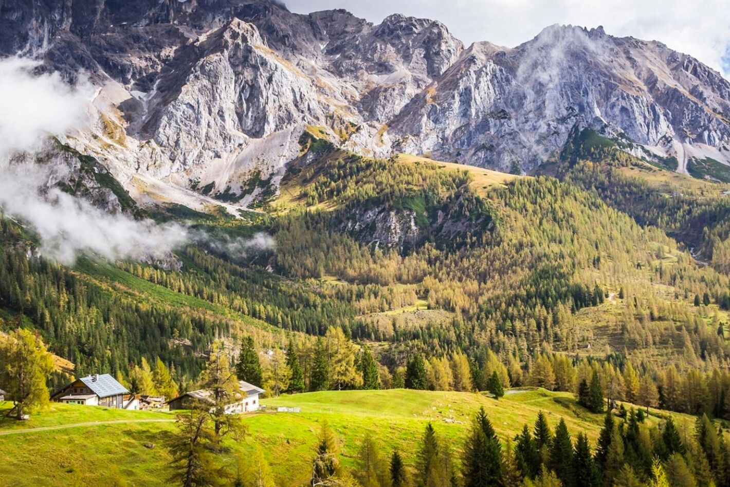 A mountainous landscape with a small house and a path leading to it.