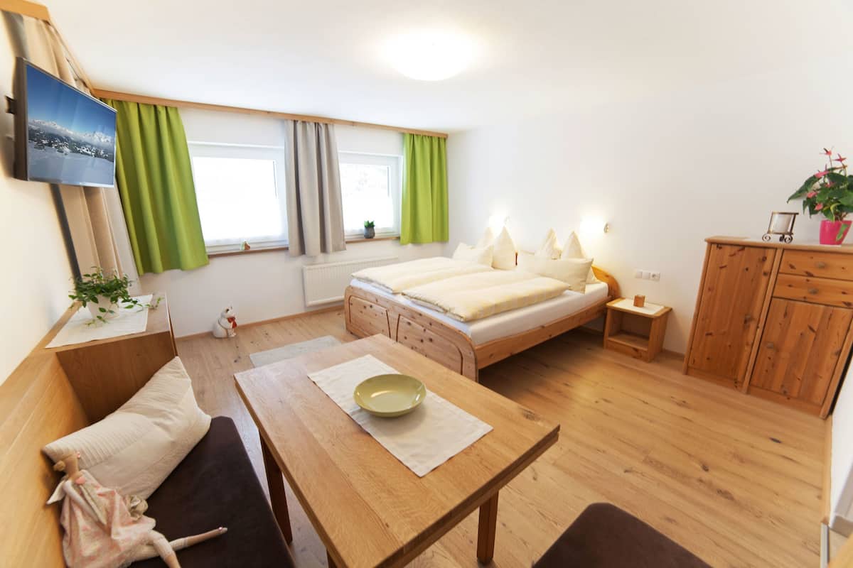 Um quarto acolhedor com uma cama, uma mesa com uma tigela, uma televisão e um armário de madeira.