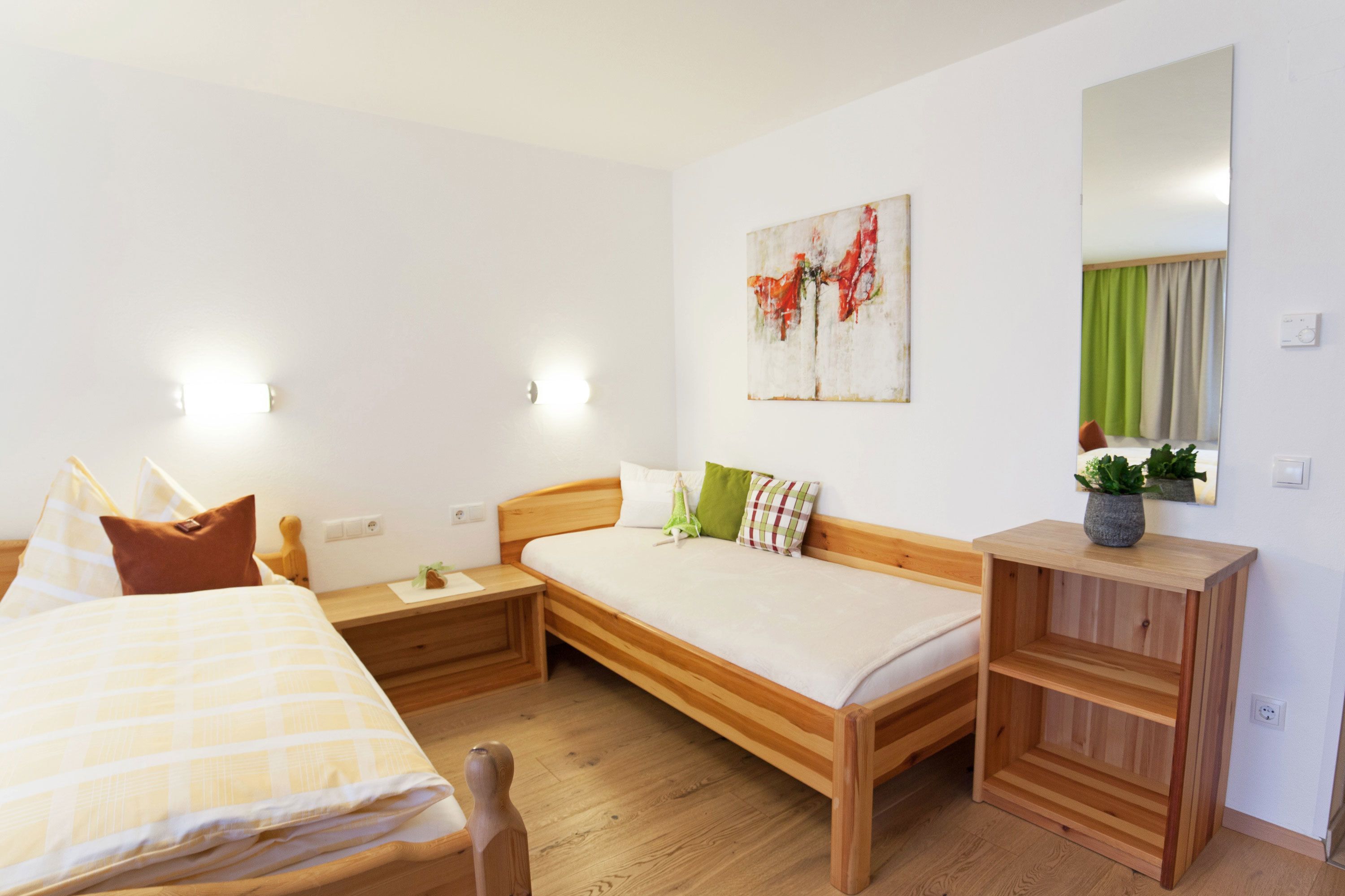 Un dormitorio con cama de madera, mesita de noche, espejo y un cuadro en la pared.