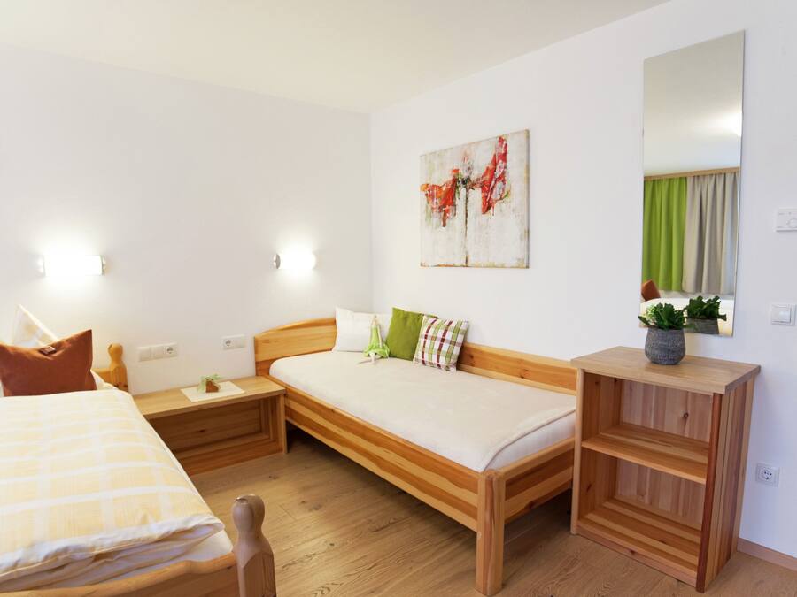 Un dormitorio con cama de madera, mesita de noche, espejo y un cuadro en la pared.