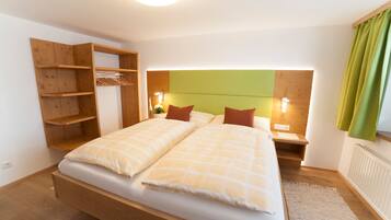 A bedroom with a wooden bed, a built-in wardrobe, bedside tables with lamps, and a green headboard.