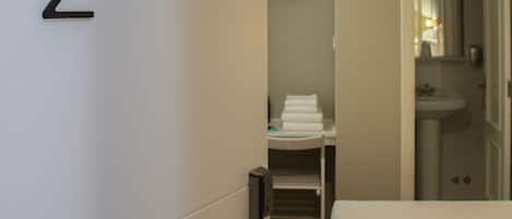 Una habitación de hotel con una cama, un baño con lavamanos y un perchero para toallas.