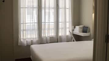 Una habitación de hotel con una cama grande, un escritorio con una silla y un televisor montado en la pared.