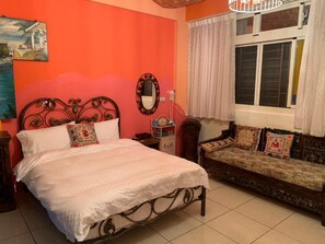 A bedroom with a bed, a sofa, a window with curtains, and a wall with a painting. - Hualien Seaside Ocean B&b (Hualien City)
