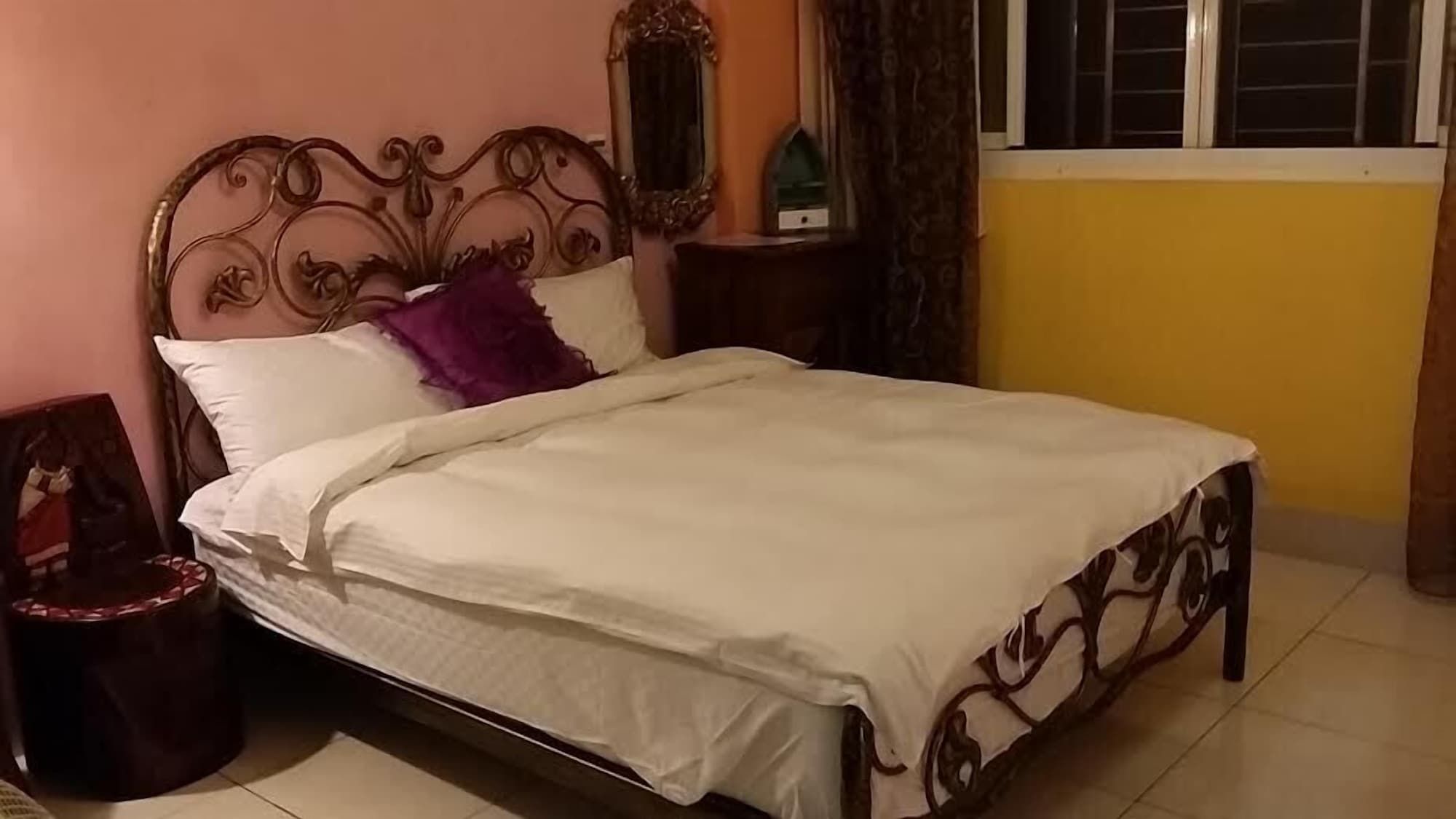 A bed with a headboard, a nightstand, a framed picture, and a window with curtains.
