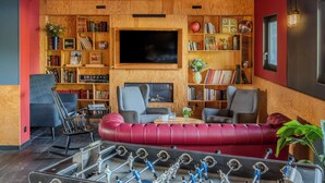 Una sala de estar acogedora con un sofá rojo, una mesa de fútbol de mesa y un televisor grande.