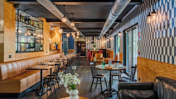 Un interior de restaurante con cabinas de madera, mesas y una zona de bar.