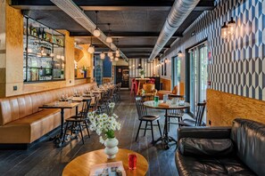 A restaurant interior with wooden booths, tables, and a bar area. - Eklo Hotels Lille (Lille)