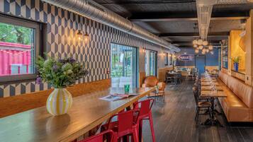 Un interior de restaurante con una barra de madera larga, sillas rojas y una pared con diseño.