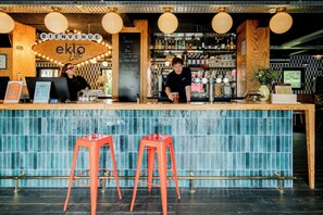 A bar with a wooden counter, two red stools, and a sign that reads 'Bienvenue eklo bar.'
