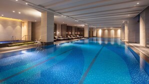 A large indoor swimming pool with clear blue water, surrounded by lounge chairs and a modern ceiling design. - Four Points by Sheraton Hefei, Baohe (Hefei)