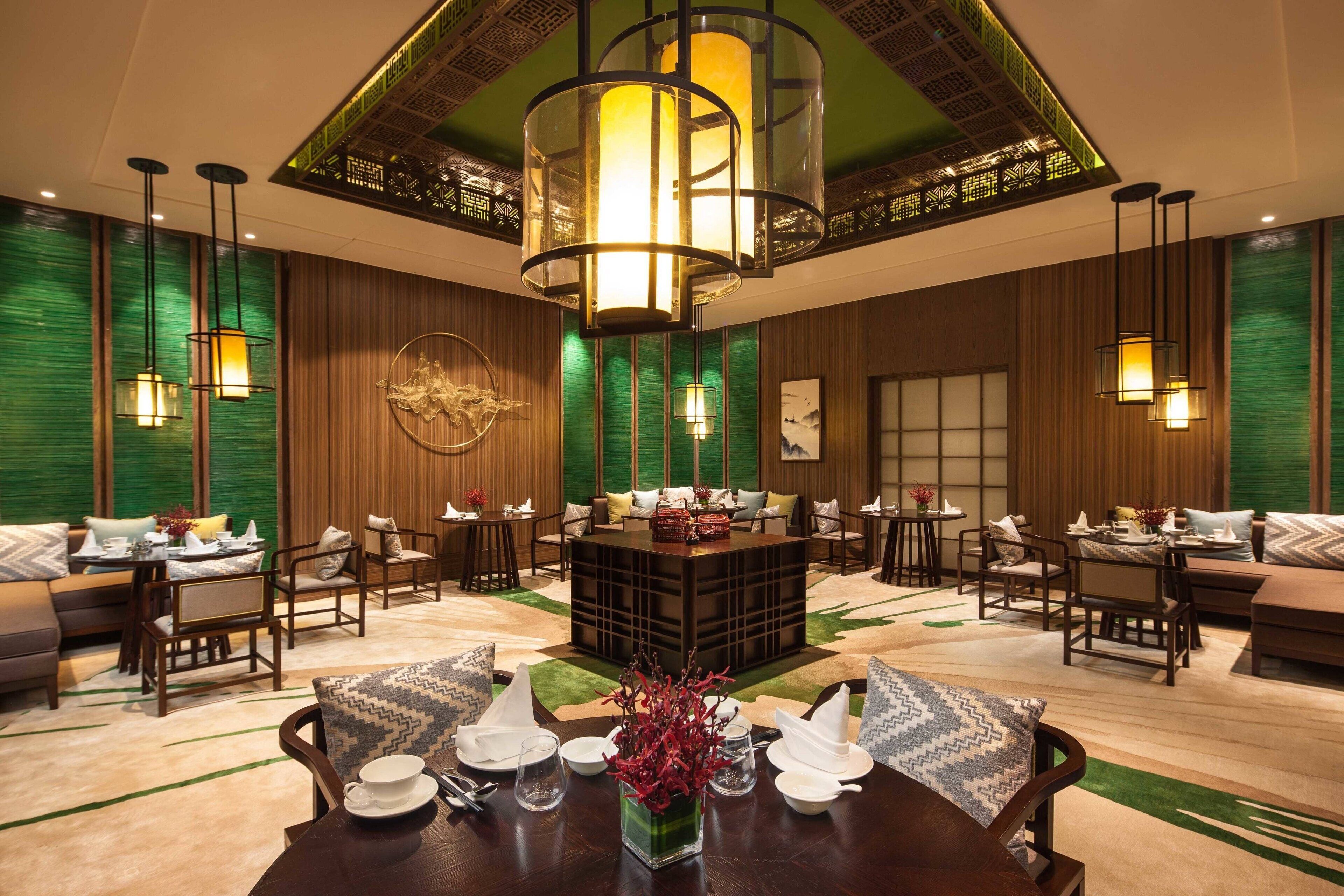 A spacious lobby with a central seating area, multiple tables, and a decorative ceiling.
