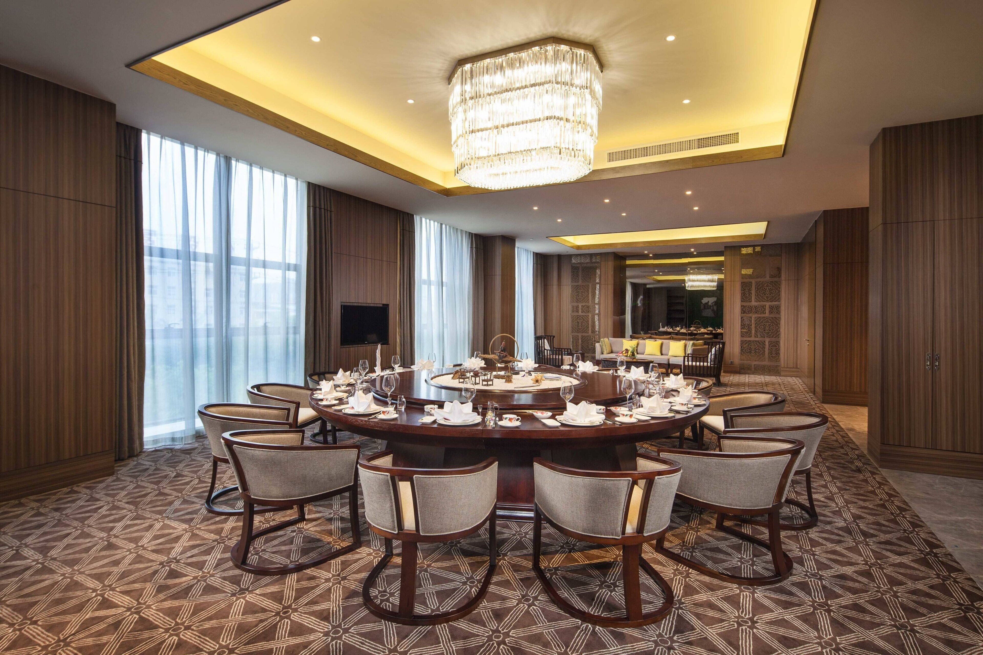 A conference room with a round table, multiple chairs, and a chandelier.