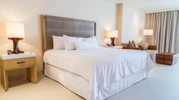 Habitación de hotel con una cama grande, dos mesitas de noche y una mesita auxiliar de madera.