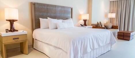 A hotel room with a large bed, two bedside tables, a nightstand, and a wooden side table.