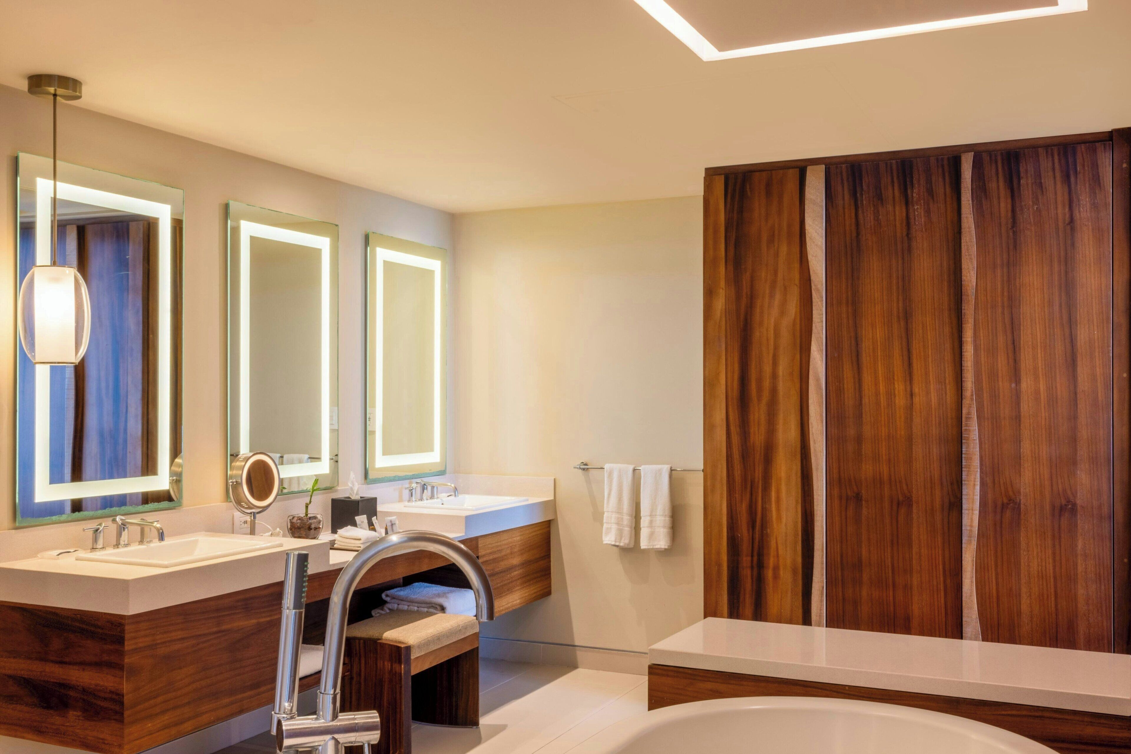 Een moderne badkamer met twee wasbakken, een grote spiegel en een wandpaneel van hout.