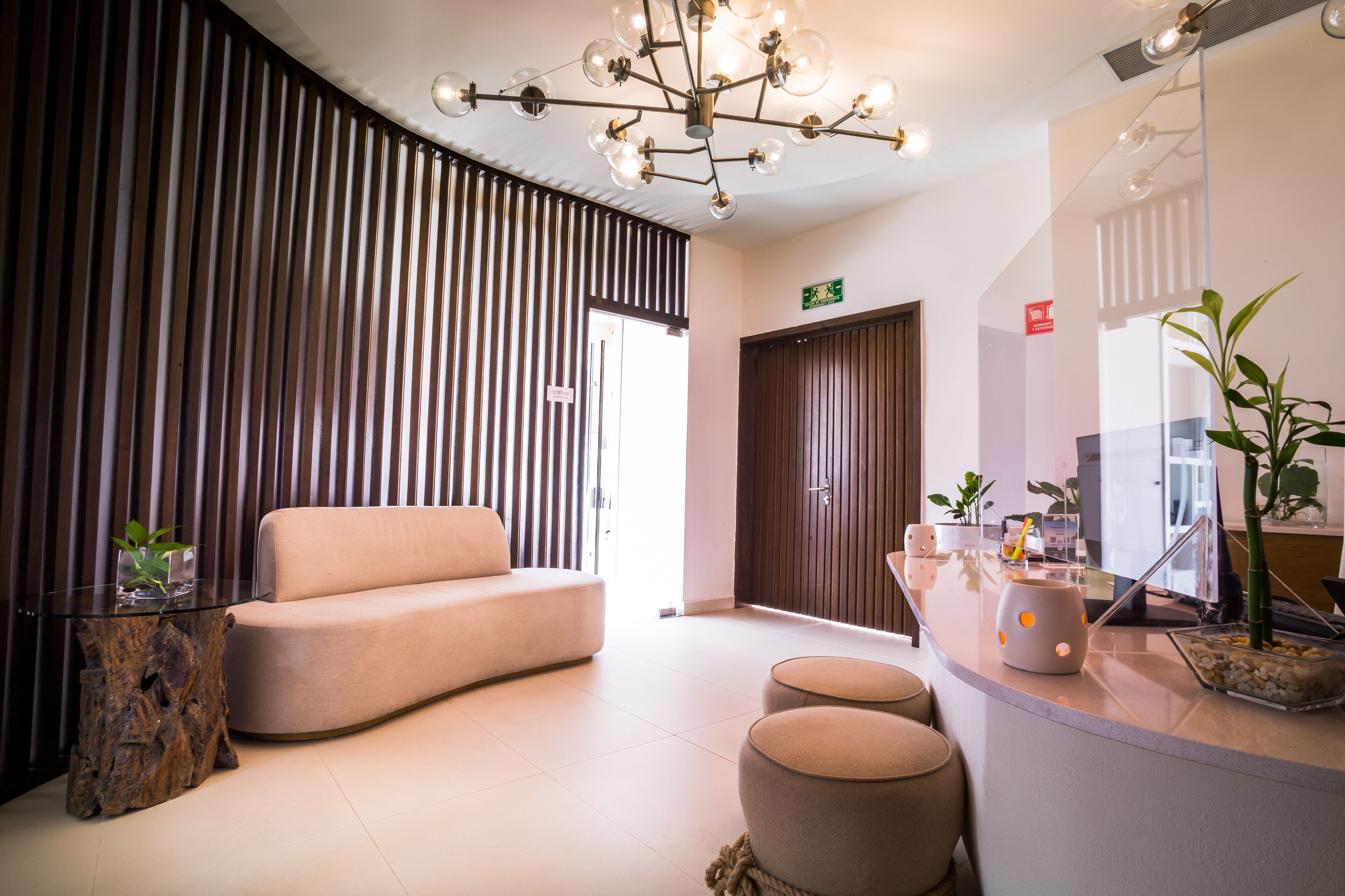 A modern lobby with a sofa, ottomans, a glass coffee table, and a wooden side table.