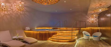 Un moderno espacio de spa con un mostrador de recepción de madera, un jacuzzi y sillones de descanso.