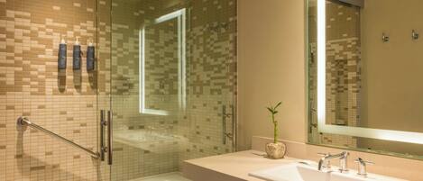 A modern bathroom with a glass-enclosed shower, a white sink, and a large mirror.
