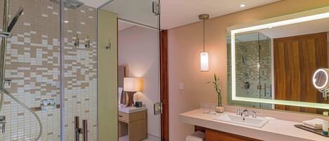 A modern bathroom with a glass shower enclosure, a large mirror, and a wooden vanity.