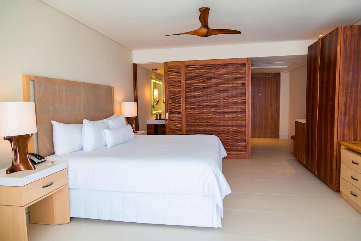 Un dormitorio amplio con una cama grande, armario de madera y ventilador de techo.