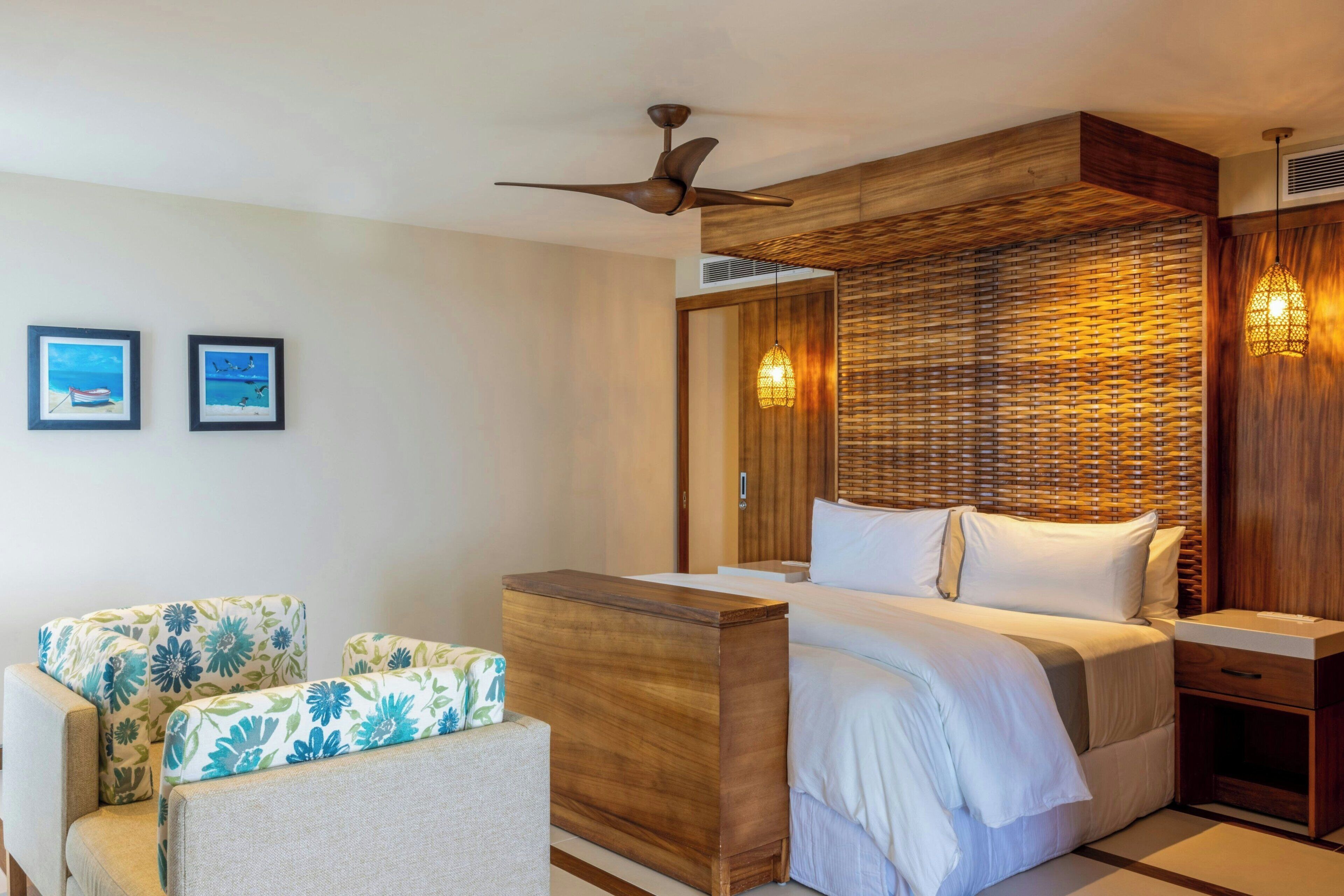 Una habitación de hotel con cama, escritorio, silla y ventilador de techo.