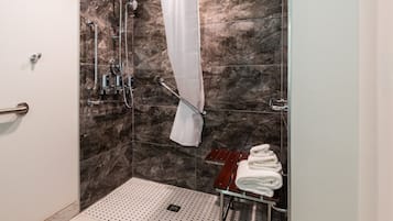 Eine moderne Dusche mit Glastür, Marmorwänden und einem Handtuchhalter mit gefalteten Handtüchern.