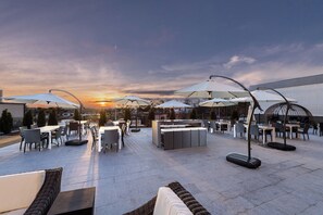 An outdoor seating area with tables and chairs, umbrellas, and a bar. - Four Points by Sheraton Atlanta Airport West (Atlanta)