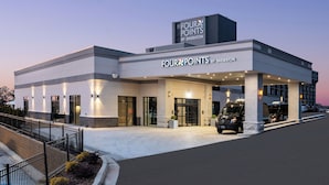 Een Four Points by Sheraton hotel met een modern design, herkenbaar aan een opvallende ingang, een overdekte parkeerplaats en een goed verlichte gevel.