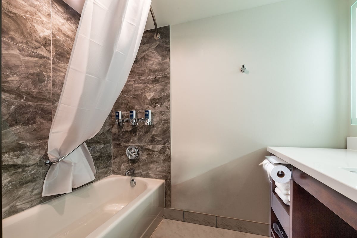 Une salle de bain avec une baignoire, un rideau de douche, des toilettes et un lavabo.